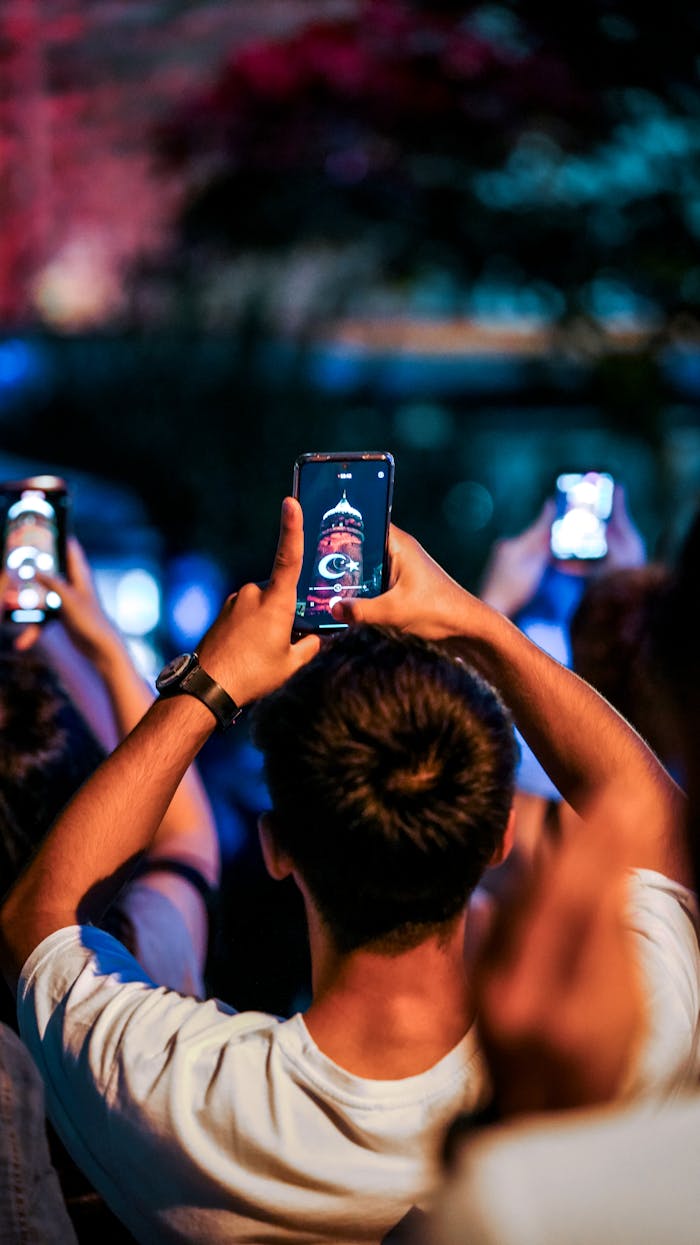 services-04 Festival attendees capturing Galata Tower in Istanbul at night with smartphones.