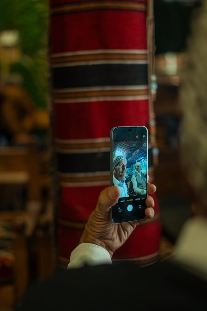 about-us-02 An elderly hand captures a moment in a Baghdad cafe on a smartphone, highlighting culture and technology.
